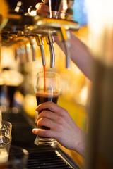 Dark beer is poured into a glass of beer tap