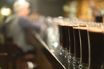 Beer glasses with dark beer are on the bar counter