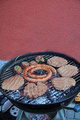 Paddies, Burger, Wurst und Fleischröllchen auf dem Holzkohle Grill 