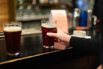 Beer glasses with dark beer are on the bar counter
