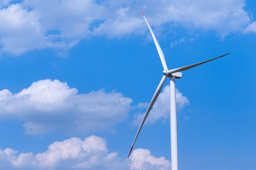 Fototapeta premium One single windmill turbine with partly cloudy blue sky in background. Renewable energy wind turbine