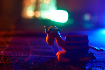 Fun orange plasticine Christmas camel on blurred background