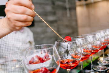 Red cocktail with strawberries. Strawberry daiquiri made with rum,brandy,lime juice, fresh strawberries,grenadine. Refreshing cocktails for a big company. A party. Soft focus.