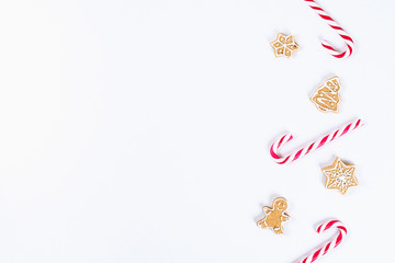Christmas layout. Striped red-white cane candies and homemade ginger cookies on a white background. New Year 2019, christmas, winter concept. Copy space, tov view, flat lay composition.
