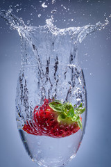 Strawberry splash plunge into water in a wine glass. 