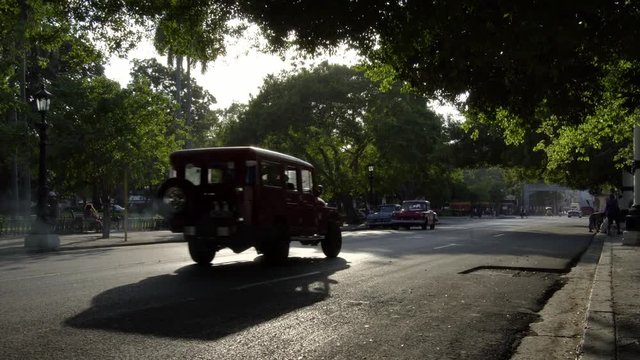 golden hour sunset,  old classic American 1950's Vintage cars drive on street in old Havana neighborhood, Cuba