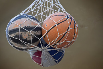 Fototapeta na wymiar Three old vintage basketball balls in mesh sack