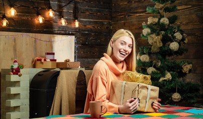 Gift emotions. Christmas gift, glamour celebration. Blonde female model dressed in a Santa Claus hat. Open Mouth. Christmas interior.
