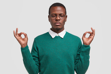 People, body language and meditation concept. Relaxed dark skinned African American man has calm...