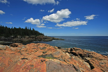 The rugged coast of Acadia National Park, Maine, under wispy clouds on a sunny summer day.