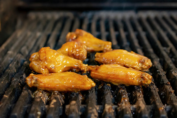 Sauced chicken wings close up on restaurant grill.