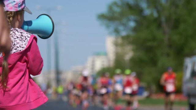 Girl cheering runners by megaphone in 4k slow motion 60fps