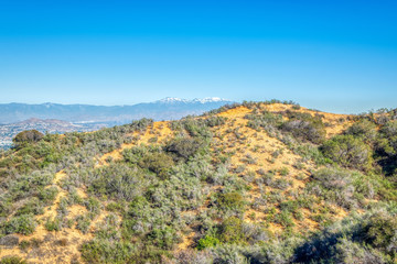 Fototapeta na wymiar Hiking trails above urban area of Southern California with blue sky for text