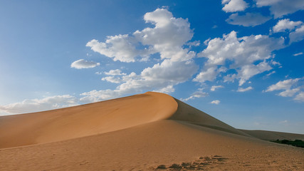 Fototapeta na wymiar Sand dunes and desert under blue sky at Mingsha Mountain, in Dunhuang, Gansu, China