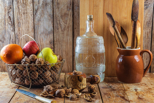 Vintage kitchen ustensil: wooden spoons, basket with fruits, nuts, bottle on the wooden background