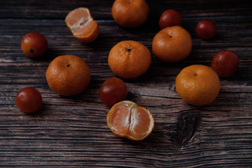 Oranges and tomatoes on the wood table on black background.