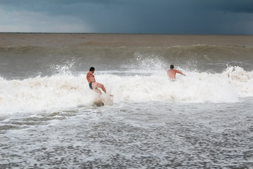 Men bathe in the sea during a storm