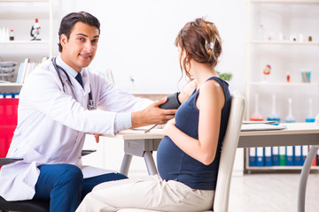 Obraz premium Young doctor checking pregnant woman's blood pressure
