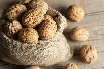whole big walnut kernel with thin shell in burlap sack on wooden vintage rustic backdrop. healthy food for brain. Fresh walnuts  background concept
