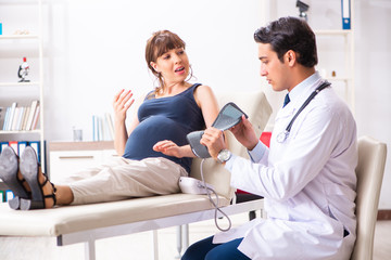 Obraz premium Young doctor checking pregnant woman's blood pressure