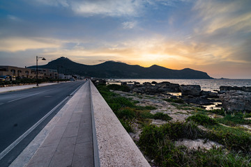 Coast road at Favignana with a beautiful susnet behind Monte Santa Caterina, Aegadian Islands, Sicily, Italy