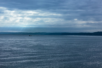 light beams fall from cloud cover on fishing boat