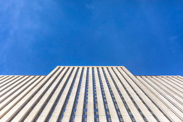 Fototapeta na wymiar Brutalist skyscraper with blue skies looking up