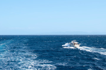 White yacht without a sail sailing on the waves of the Mediterranean Sea. A small ship in the sea alone, summer. Boat trip on a small boat