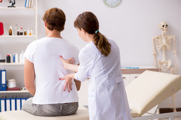 Fototapeta premium Male patient visiting young female doctor chiropractor 