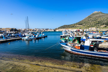Fototapeta na wymiar Traditional colorful fishing boats at Favignana harbor in a beautiful sunny day, Aegadian Islands, Sicily, Italy