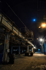 Dark and eerie urban city alley with a vintage railway bridge and the moon at night