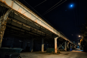 Obraz premium Dark and eerie urban city alley with a vintage railway bridge and the moon at night