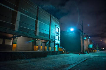 Scary industrial urban street city night scene with train loading docks by vintage factory...