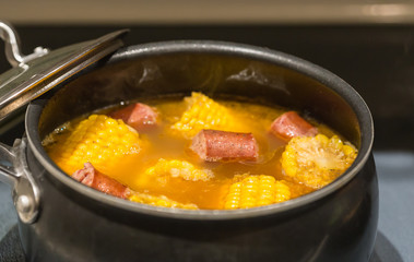 Corn on the Cob and Sausage Boil:  Corn on the cob and sausage boil on top of the stove in pot with lid off.