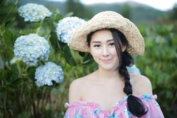 Fototapeta premium Beautiful girl with a field of hydrangea flowers.