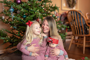 Happy young mom with little daughters on Christmas morning