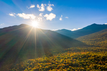 Aerial shot with sun rays flaring at sunset from behind Mount Washington, New Hampshire, on a late...
