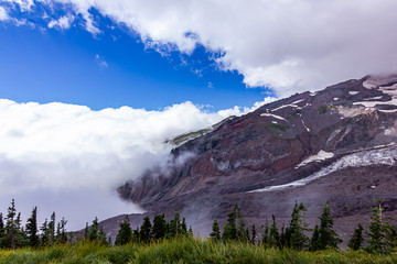 dark mound of purple mountainside near green meadows