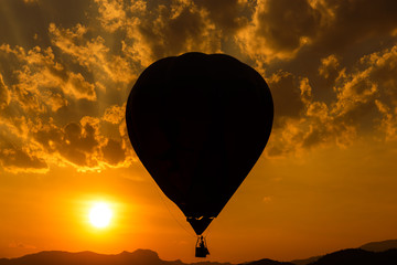 Silhouette hot air balloon over mountains in sunset sky 