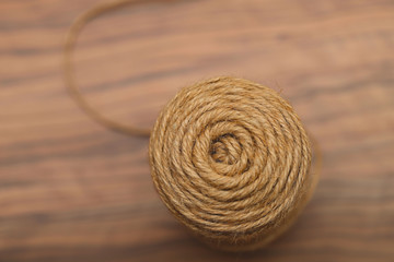 Background texture of a circle of a coil of natural hemp rope on a wooden table. Cropped shot, close-up, horizontal, abstract, top view