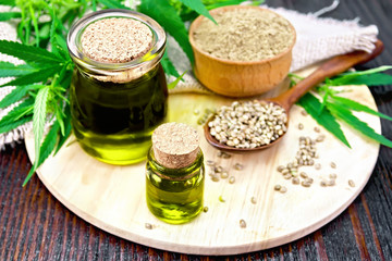 Oil hemp in two jars with flour on dark board