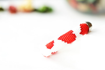 Fototapeta na wymiar Bead crochet bracelet white color with red hearts print close up