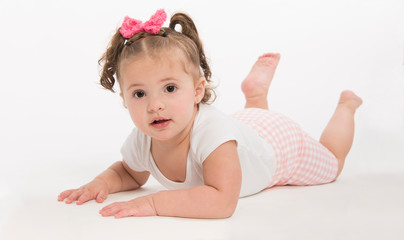 Sweet, baby  girl with pink hair bow, lying in onesie on white background