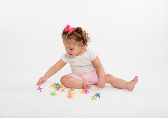 Little. curly hair girl, sitting, playing with jacks, isolated on white background