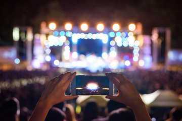 Hand holding smartphone photographing live concert , People taking photographs with smart phone...