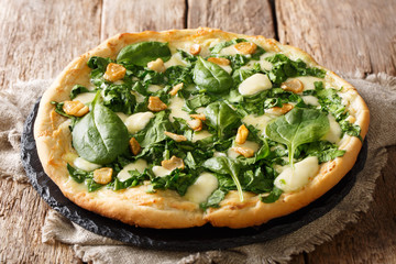 Italian white pizza recipe with fresh spinach, garlic and cheese close-up on a board. horizontal