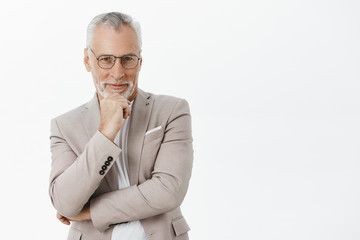 Intrigued and pleased good-looking old male with white beard and moustache in black frames and...