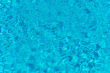 Blue water in swimming pool background. Ripple Water in swimming pool with sun reflection. Blue swimming pool rippled water detail.