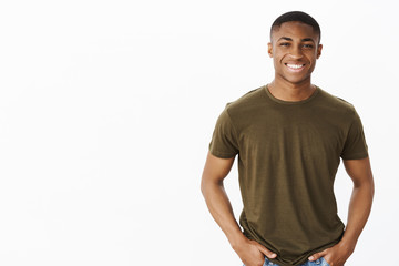 Nice african american guy smiling at camera while standing in casual pose in hucky t-shirt with...