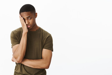 Portrait of man feeling embarrassed making facepalm gesture putting hand to half of face peeking at...